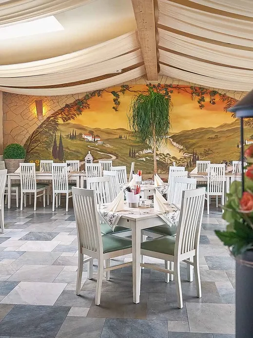Innenraum des Restaurants Casa Vina mit mediterran-vietnamesischem Wandgemälde und weiß gedeckten Tischen